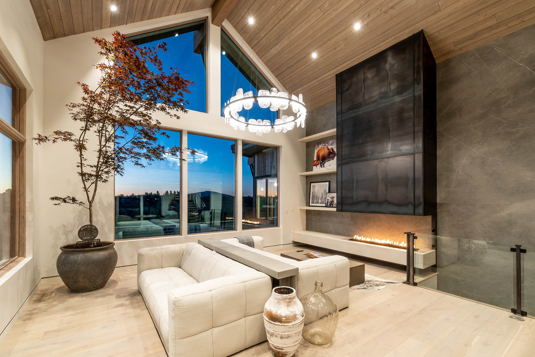 Great room with a vaulted ceiling, blackened-steel fireplace, and walls of glass to the canyon