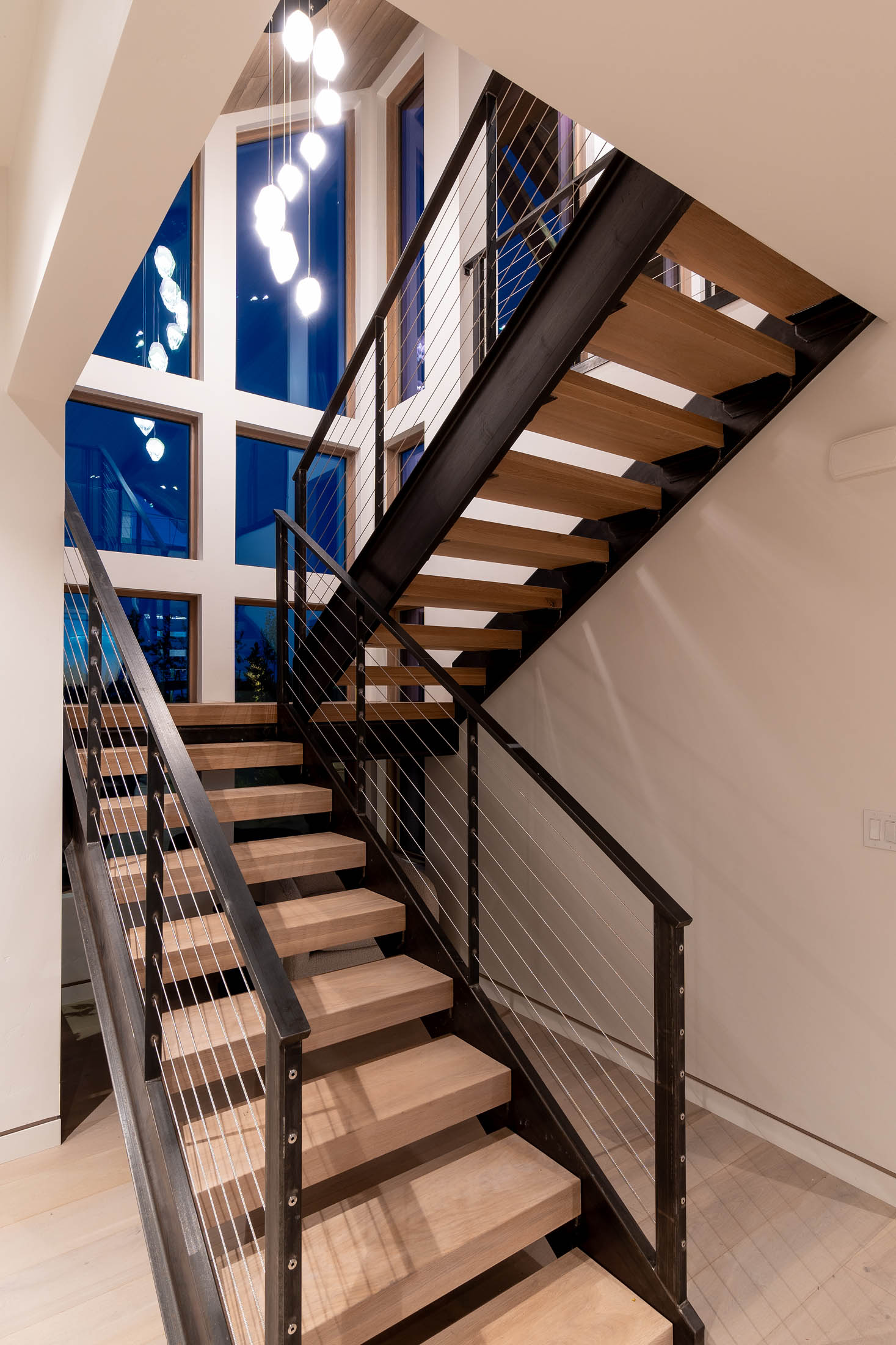 Floating steel-and-wood staircase beside a tall canyon-facing window