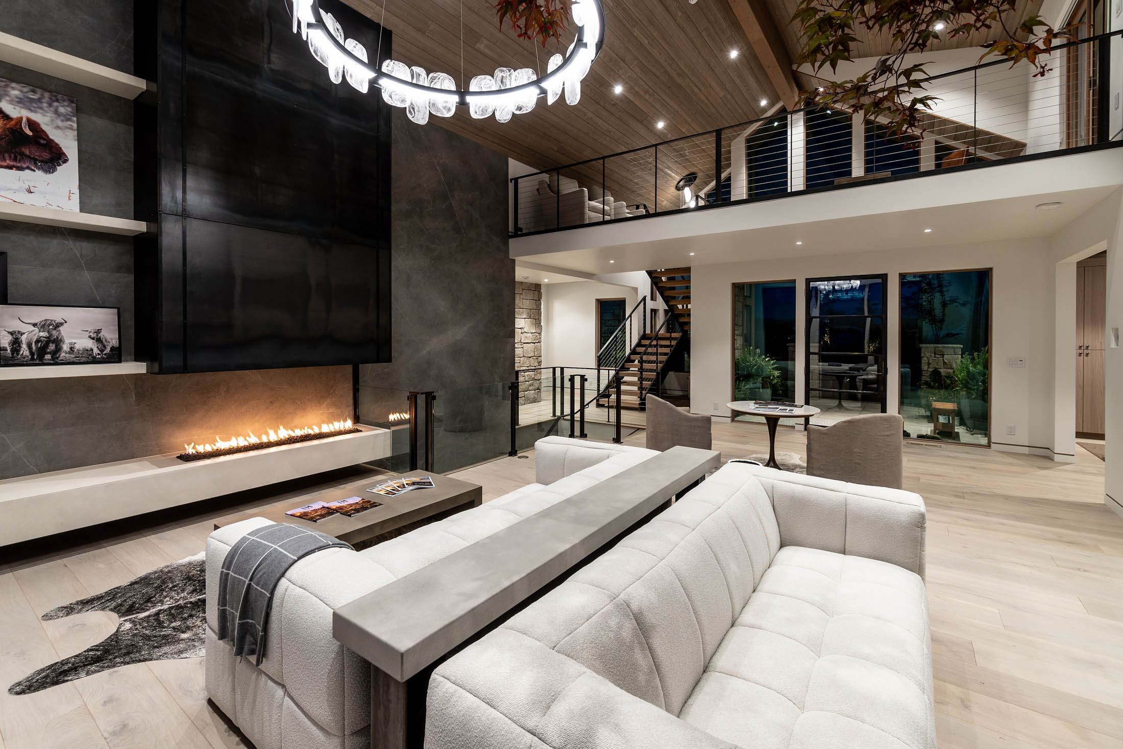 Great room open to a loft with a linear fireplace and layered seating
