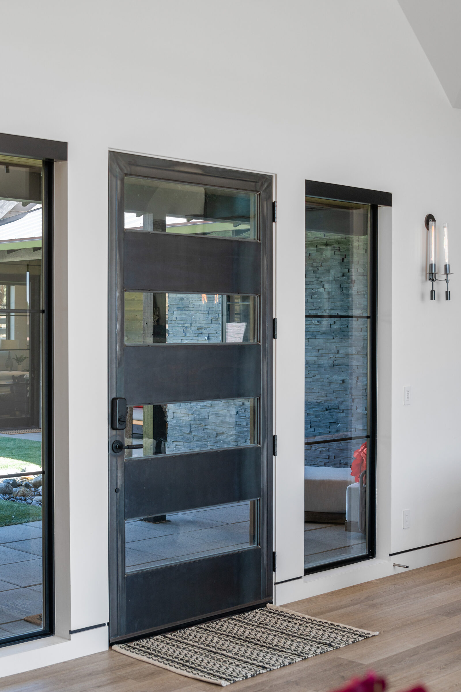 Glass-and-steel pivot entry door flanked by sidelights