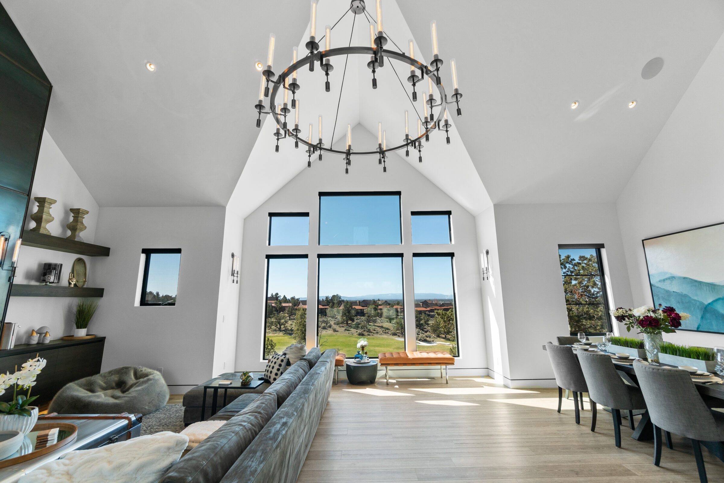 Great room with a vaulted ceiling, iron chandelier, and full-height walls of glass