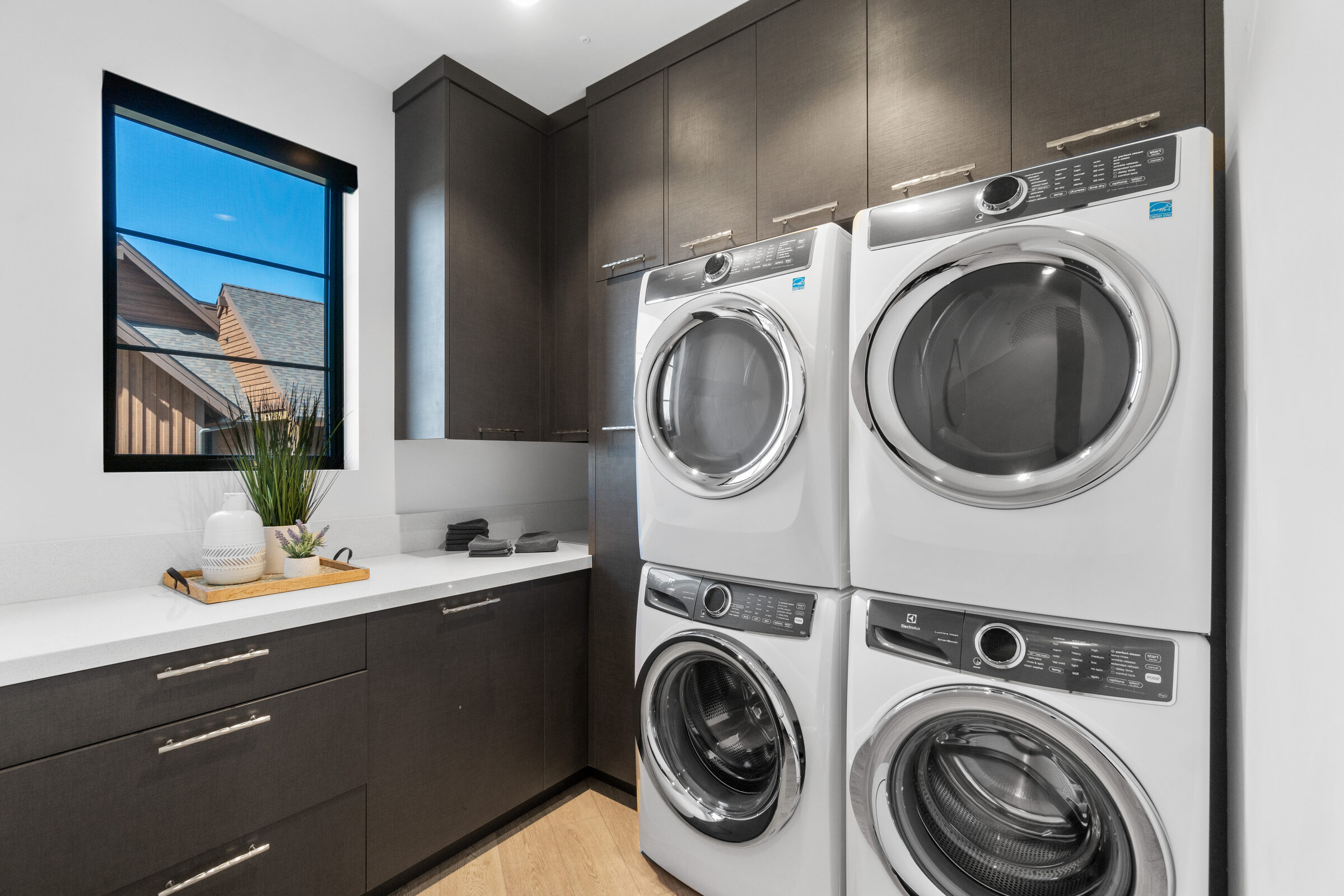 Laundry room with a stacked washer and dryer and dark cabinetry