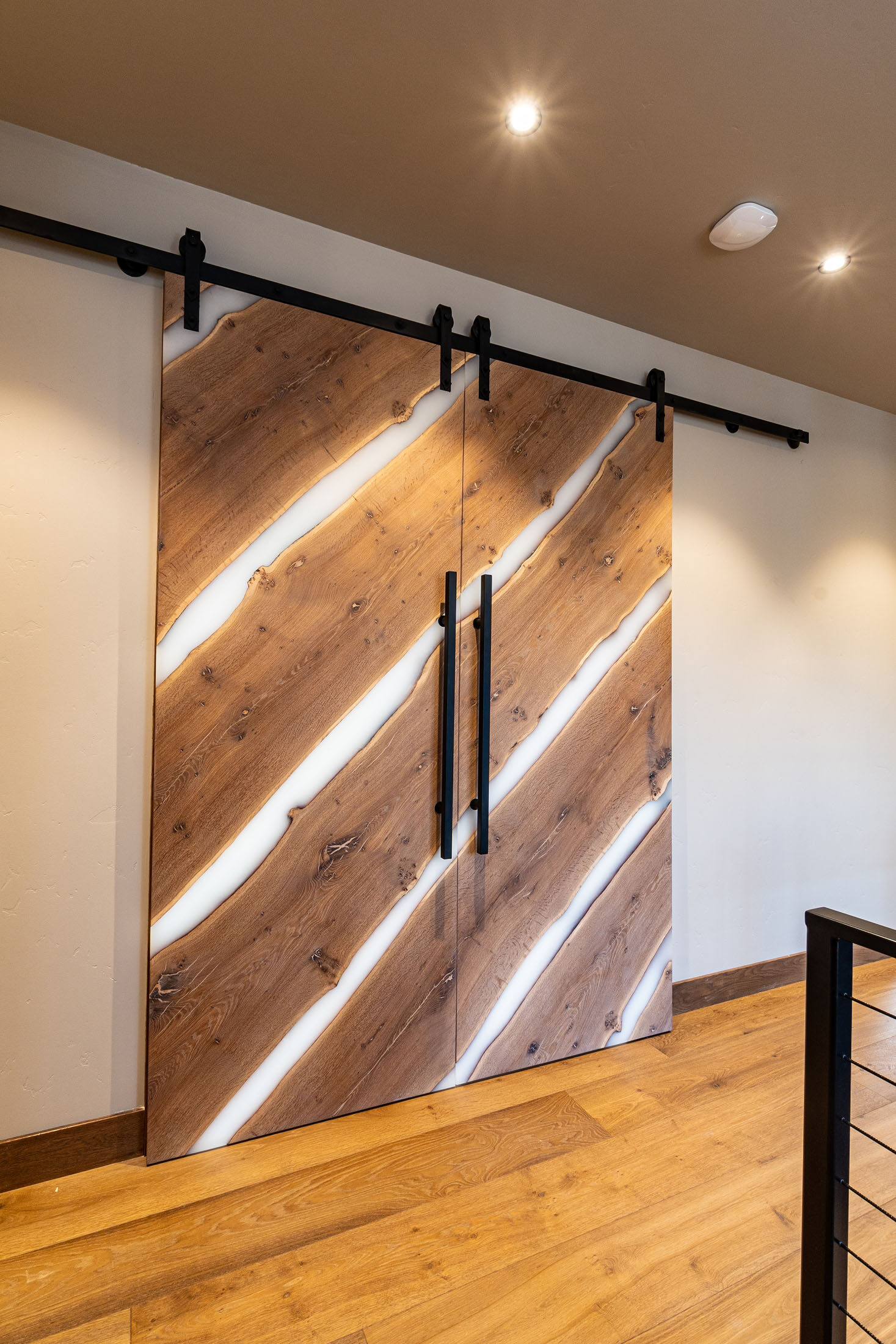 Live-edge barn door with integrated LED lighting in a wood-floored hall