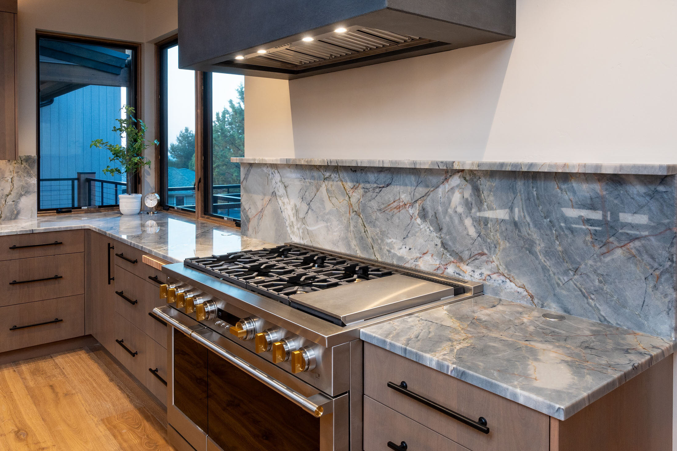 Kitchen with blue quartzite counters and backsplash, wood cabinetry, and a professional range