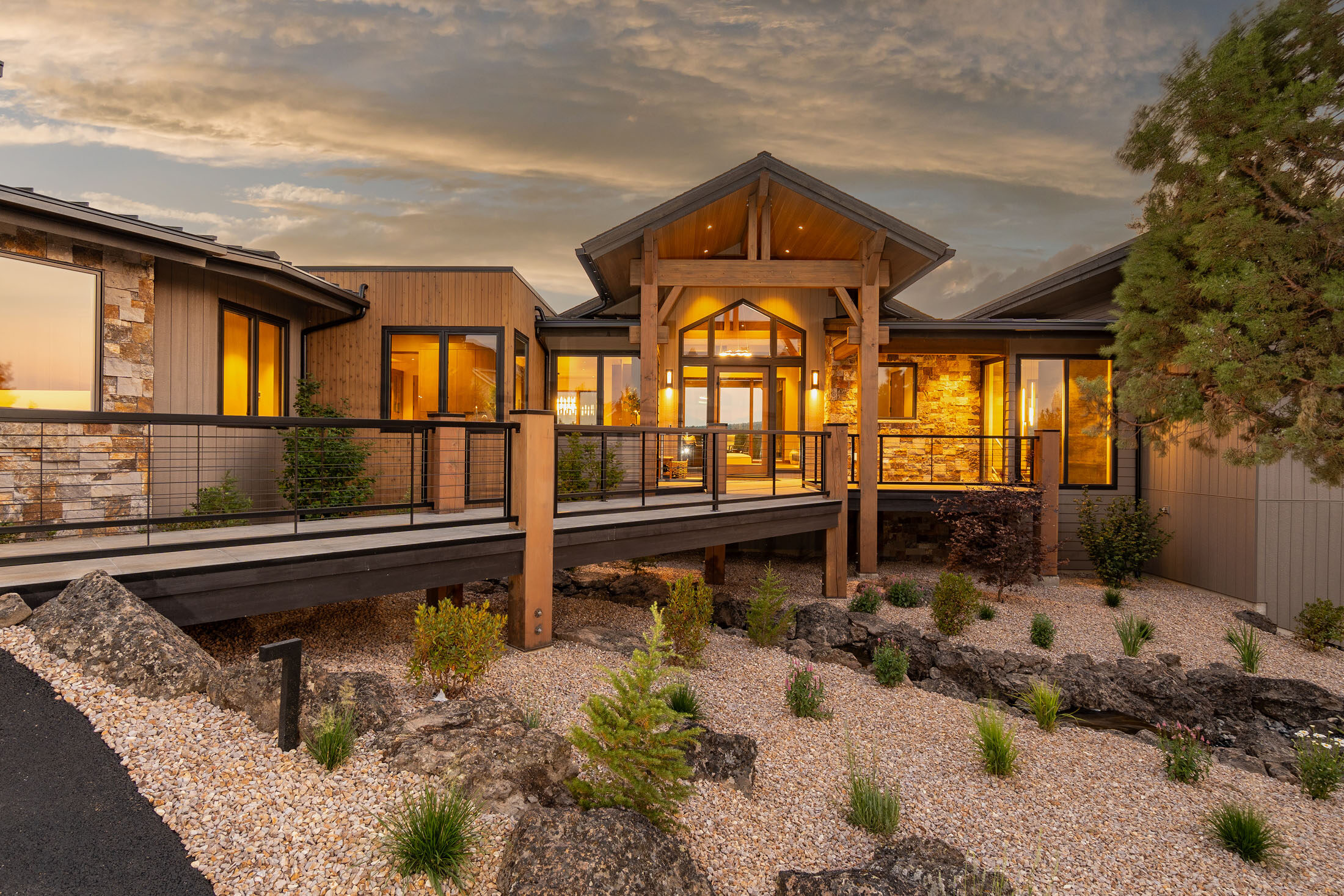Rear elevation at dusk with timber posts, glass walls, and a wraparound deck, Eagle Crest