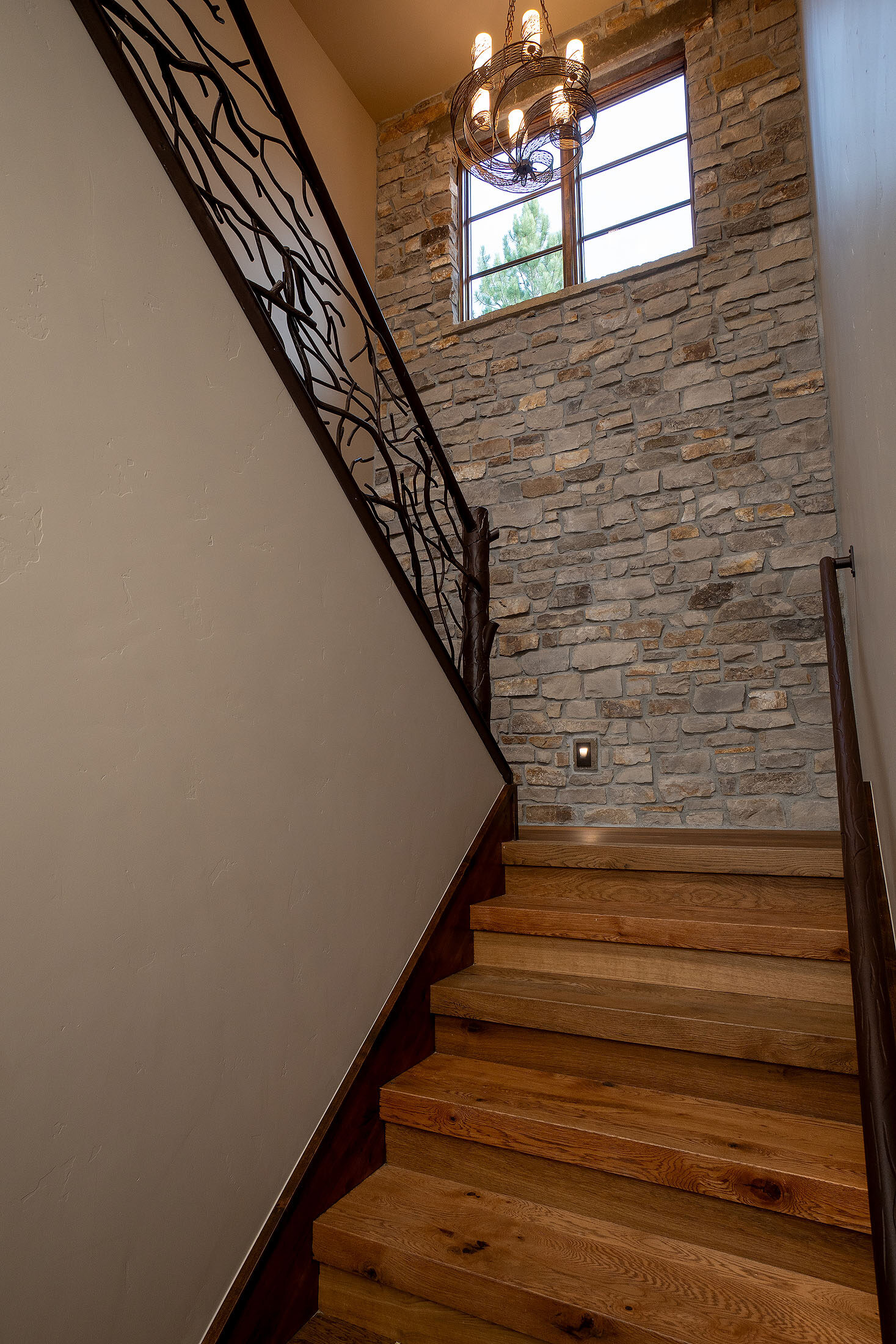 Staircase with a forged-iron railing against a stacked-stone wall