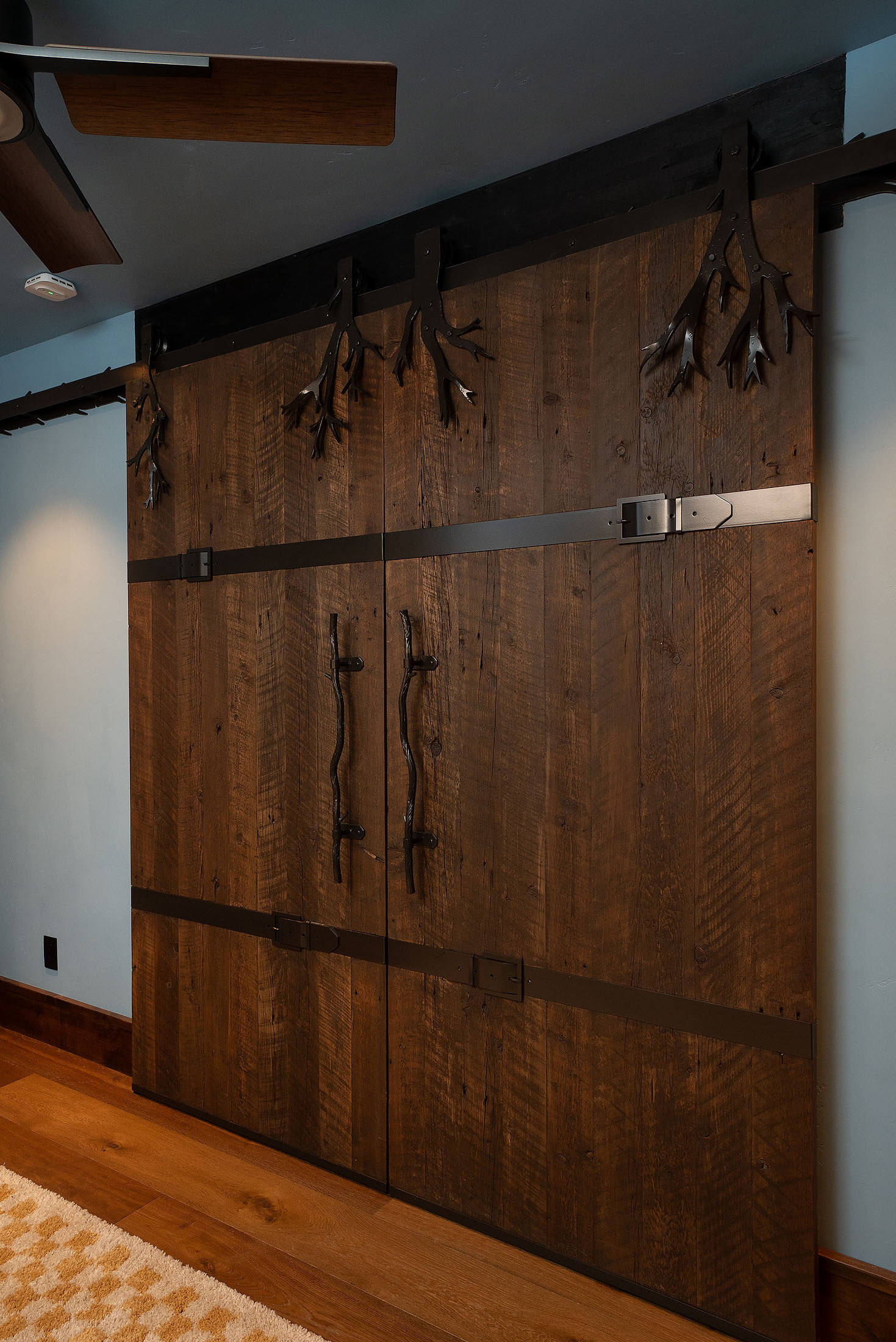 Reclaimed-wood sliding barn doors with forged antler pulls