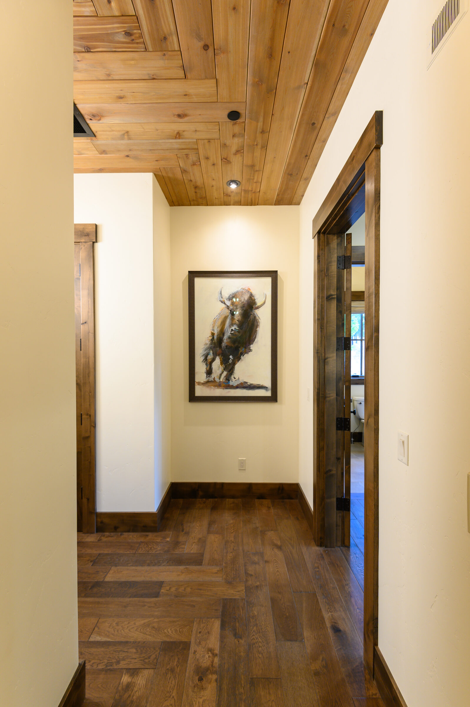 Wood-floored hallway with bronze art