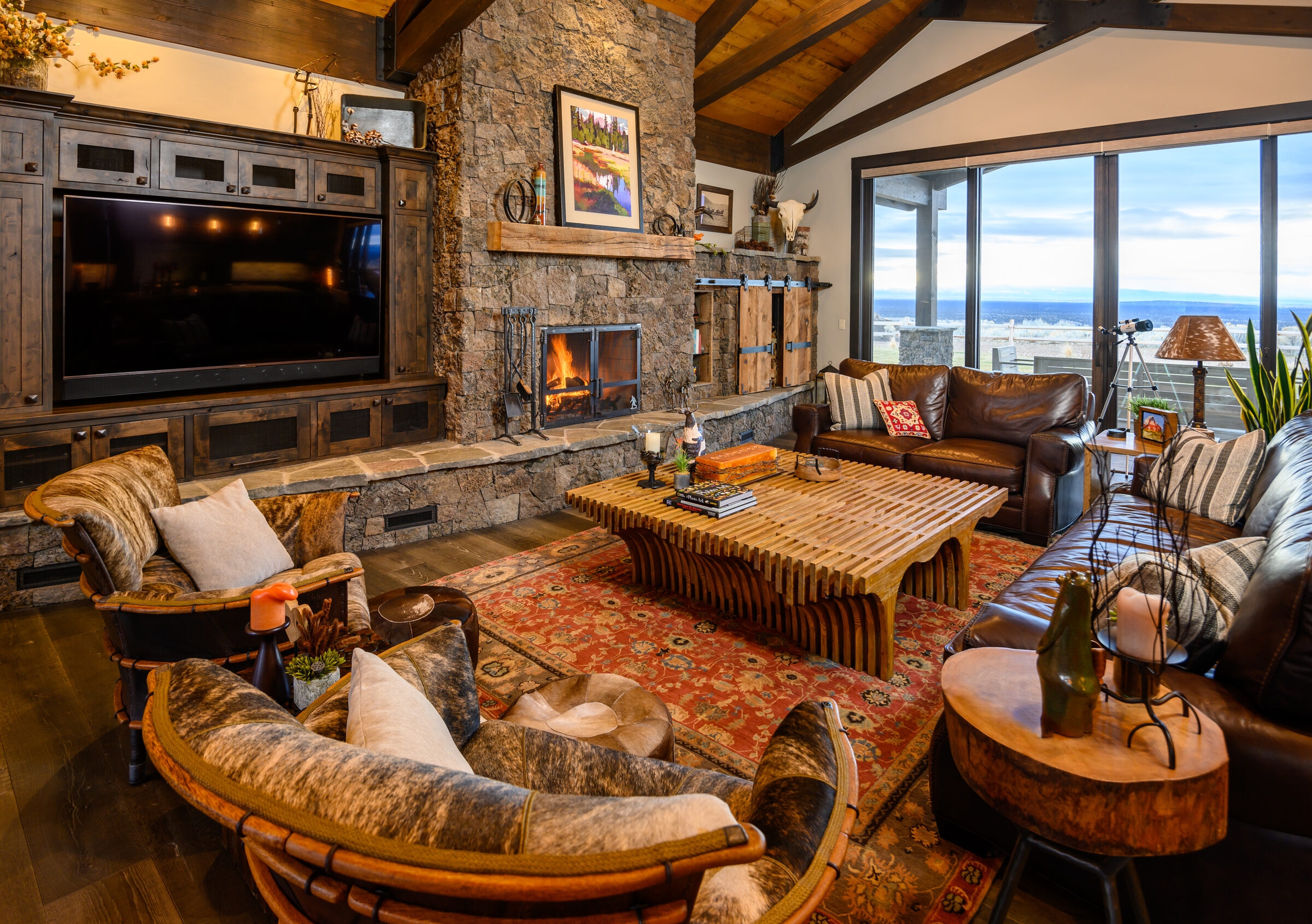 Great room with a full-height stone fireplace, leather seating, and wraparound mountain views, The Lookout