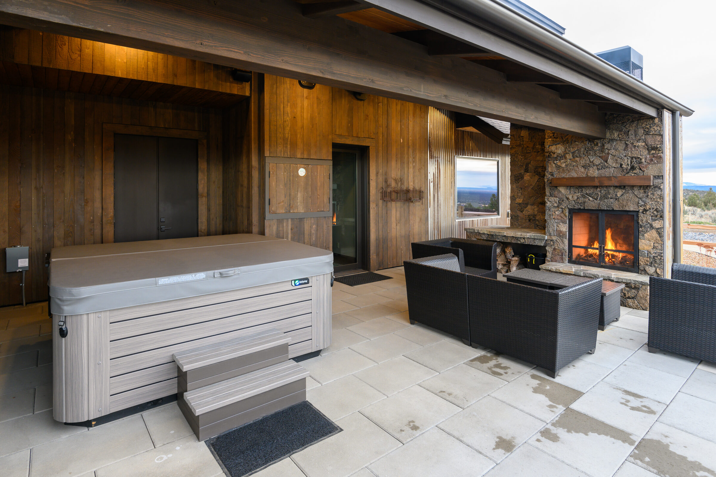 Outdoor terrace with a hot tub and fireplace at the butte's edge