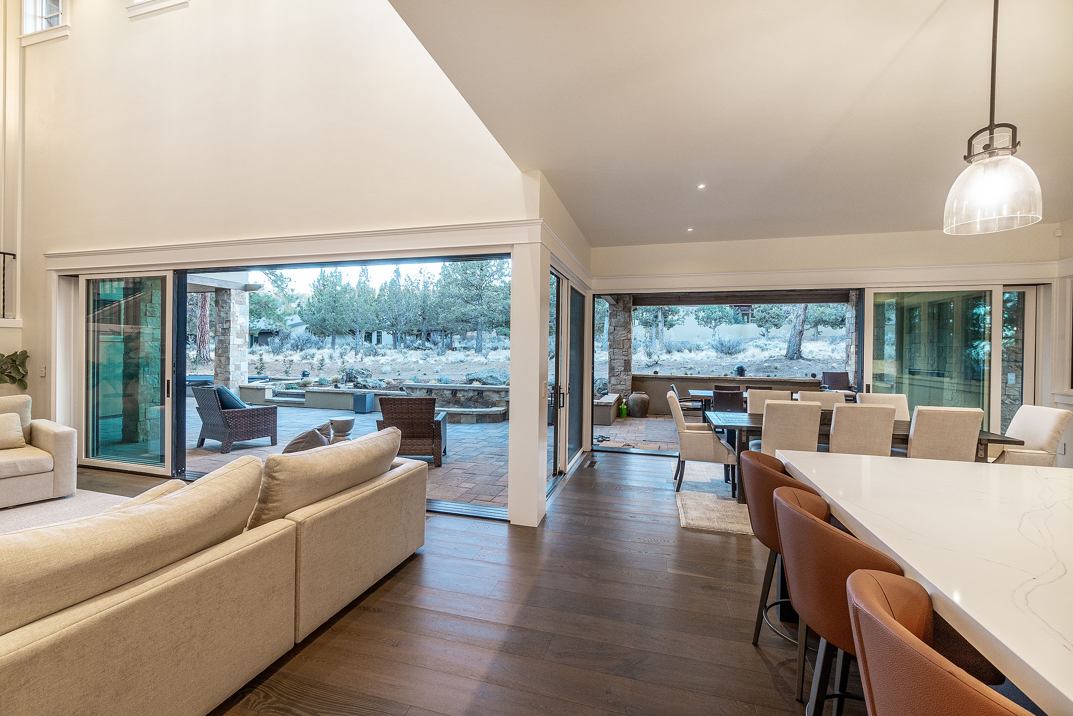 Living and dining opening through glass walls to a covered patio at the Sunrise North Rim residence, Awbrey Butte