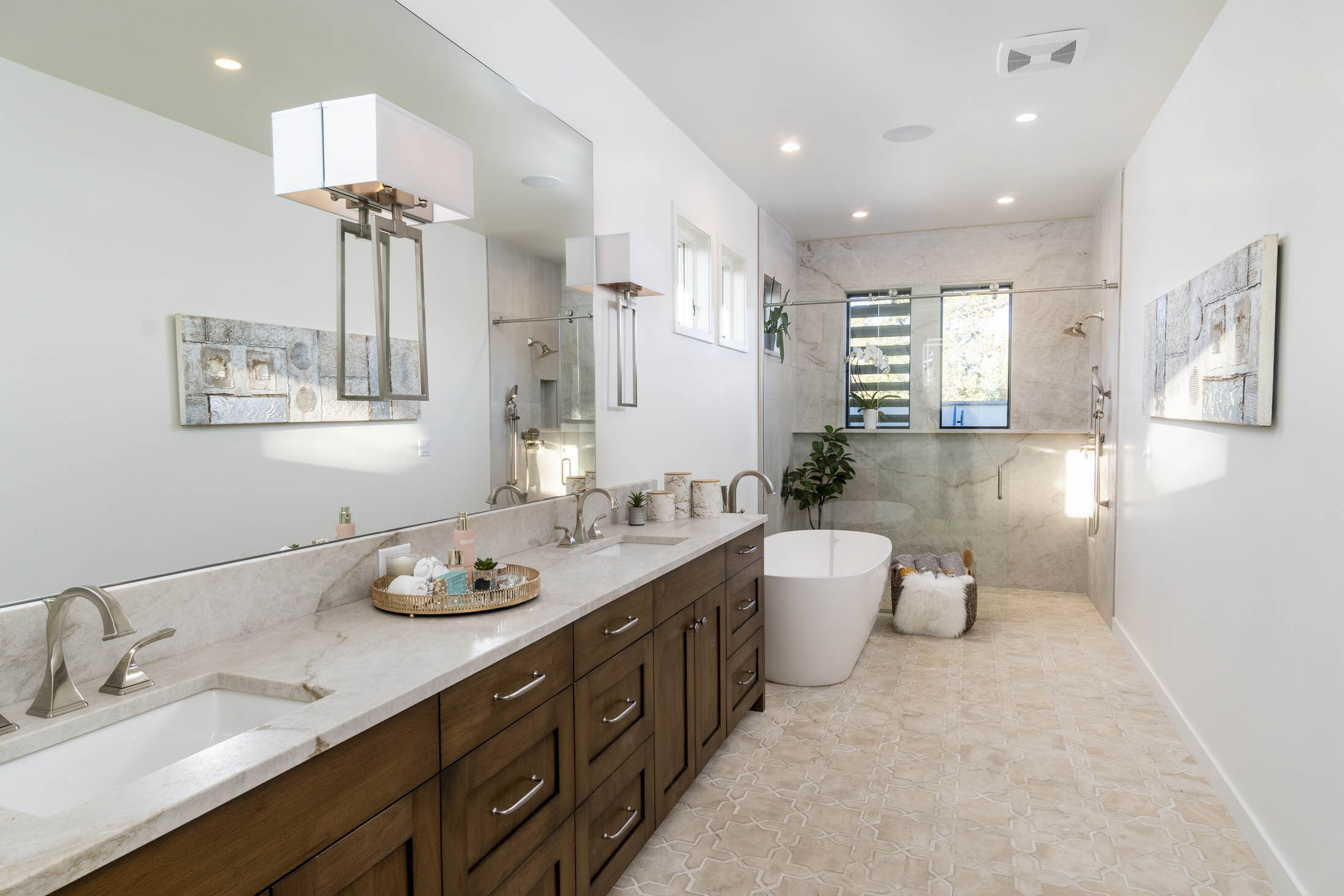Primary bath with a double vanity, freestanding tub, and glass shower
