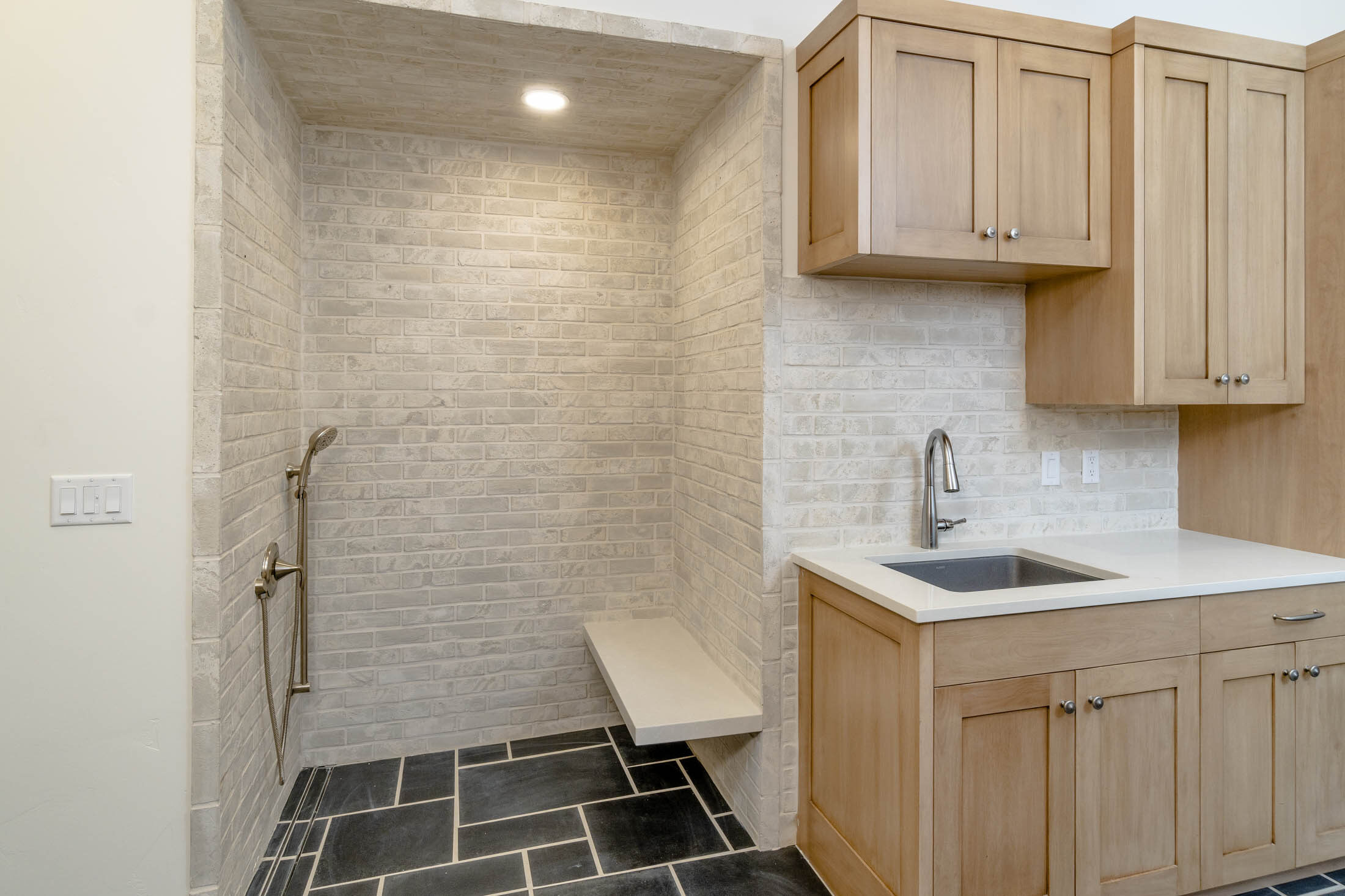 Utility room with a tiled bench niche, prep sink, and wood cabinetry