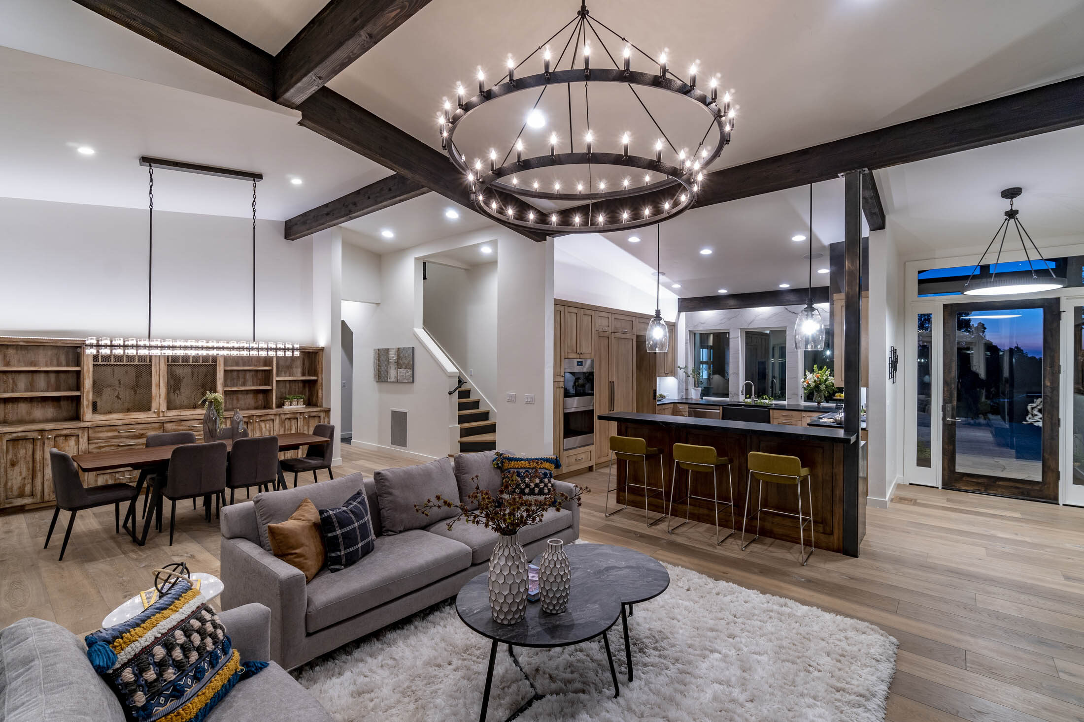 Great room with exposed beams, an iron ring chandelier, and an open stair, Juniper Preserve