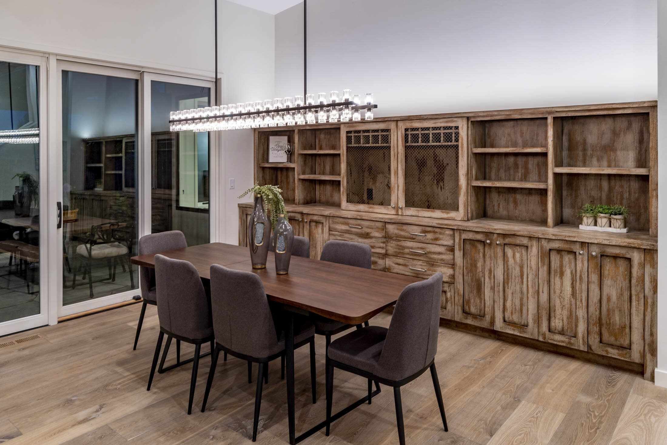 Dining area with a live-edge table beneath a linear chandelier and a built-in wood hutch