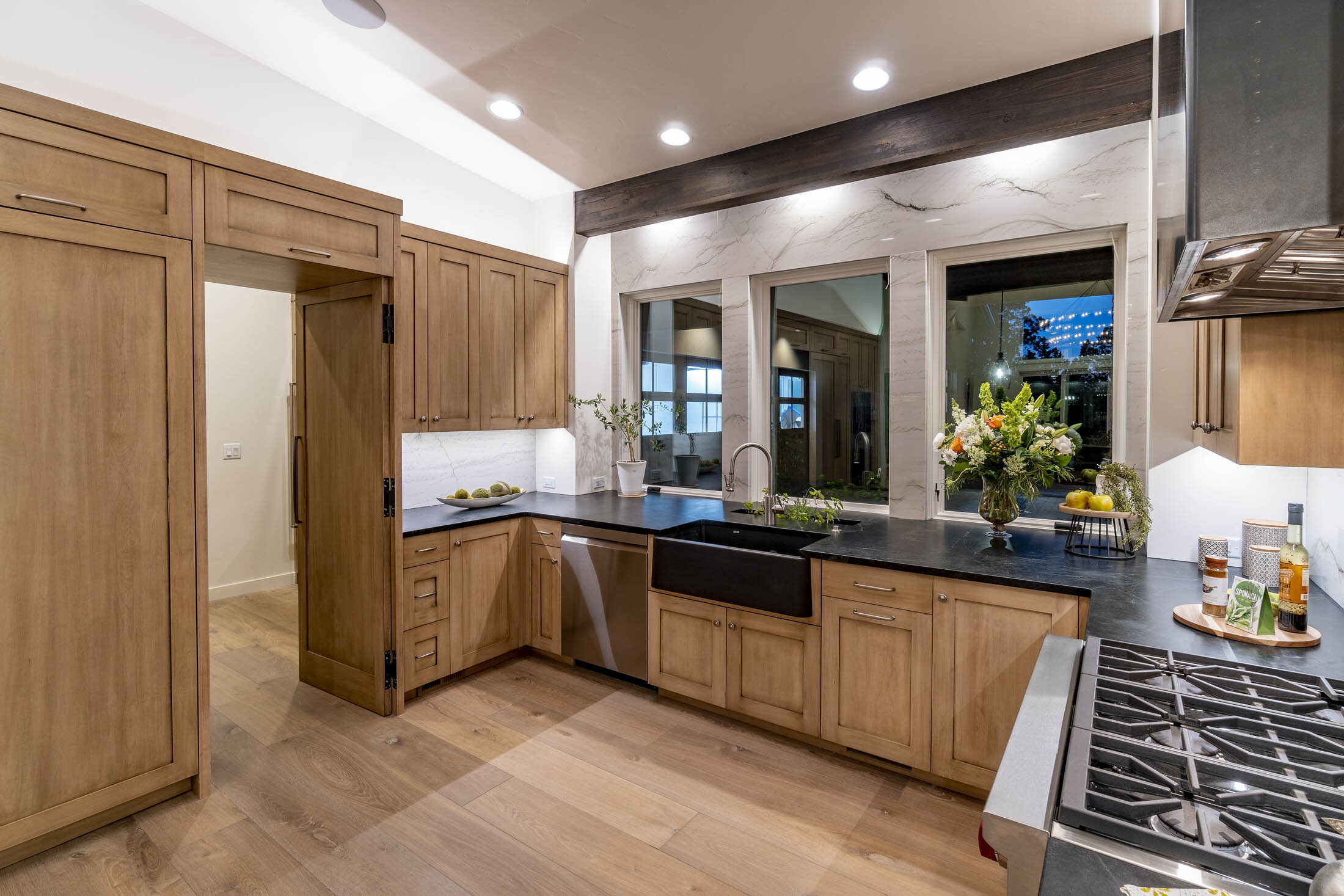 Kitchen with white oak cabinetry, dark stone counters, and a farmhouse sink