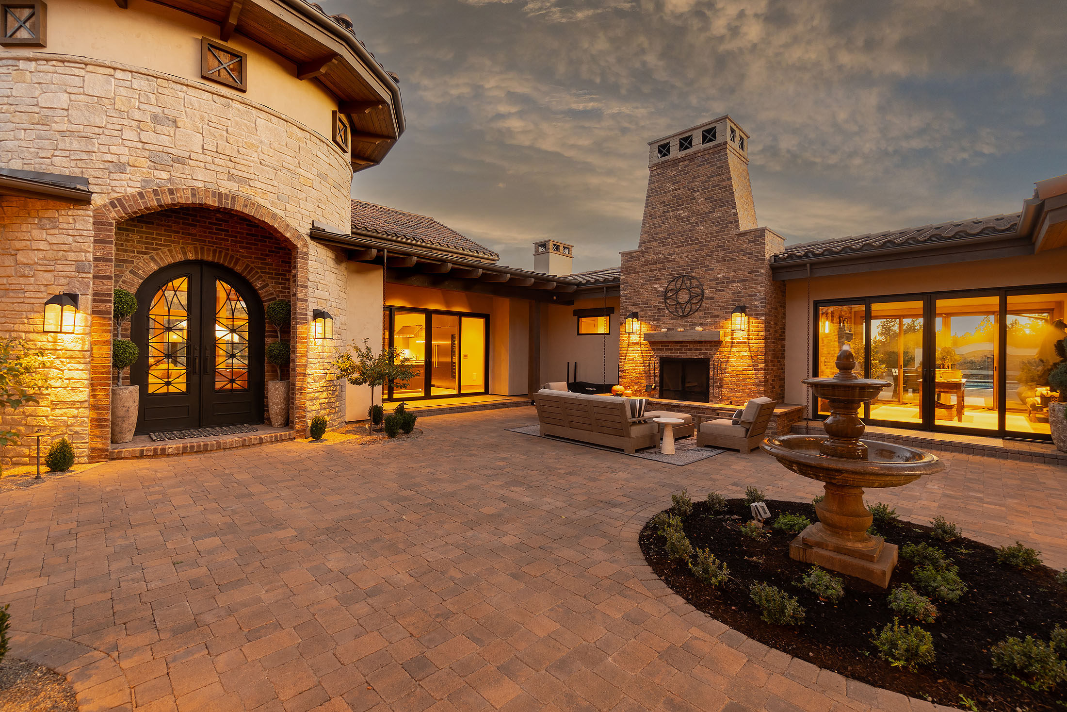 Stone courtyard with fountain and arched entry at dusk at the Sunrise Cliff Side Ranch Estate, Ranch at the Canyons