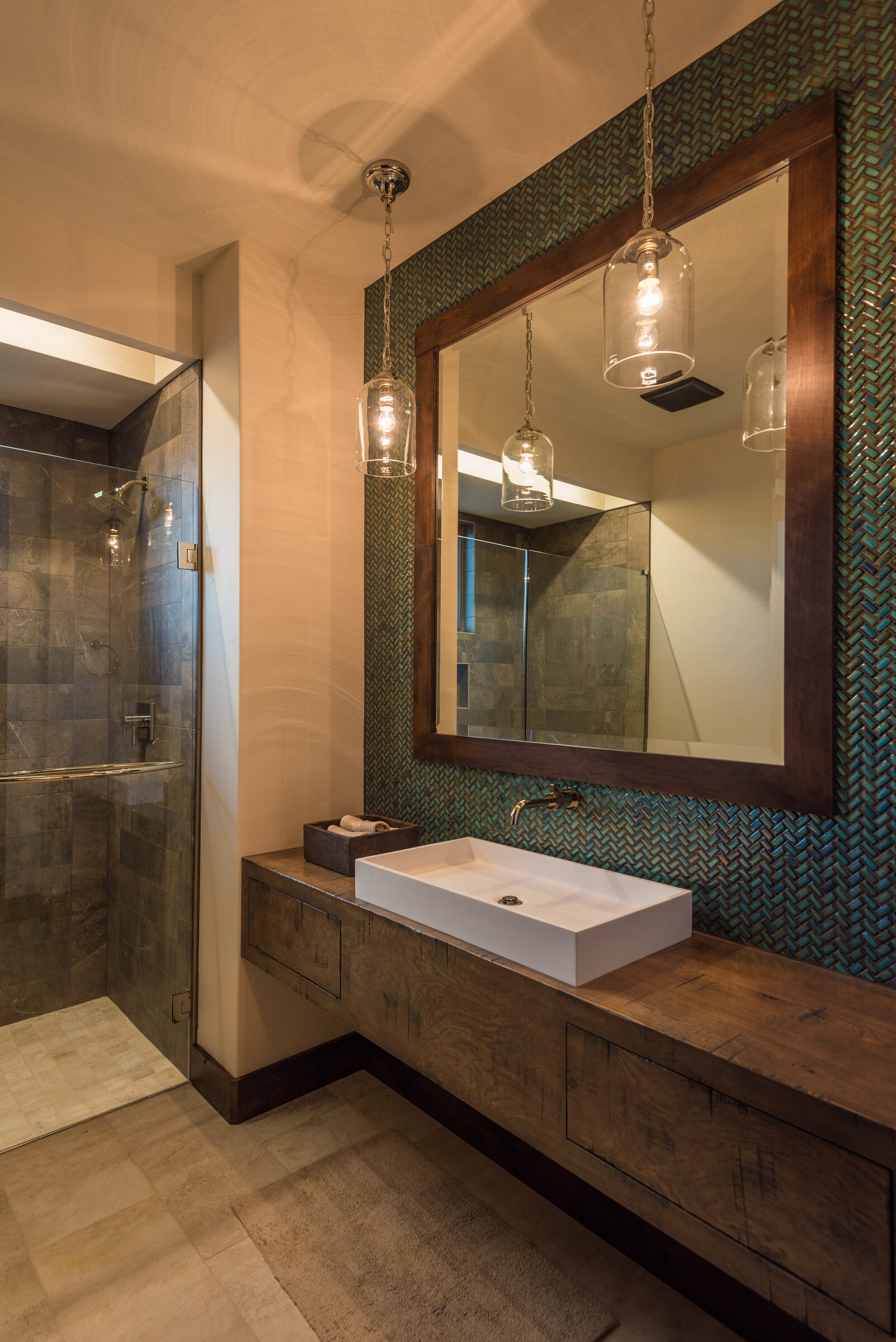 Powder room with a stone vessel sink and a mosaic-tiled mirror wall