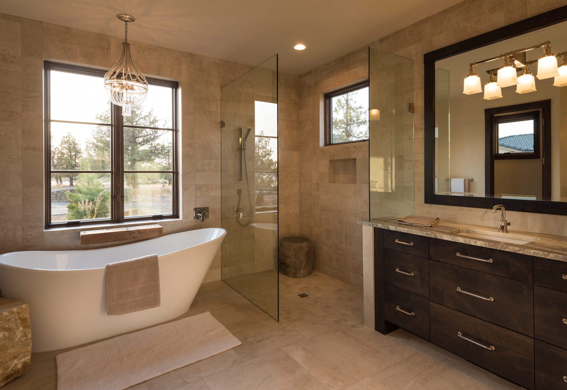 Primary bath with a freestanding tub, walk-in shower, and dual vanities framing a window