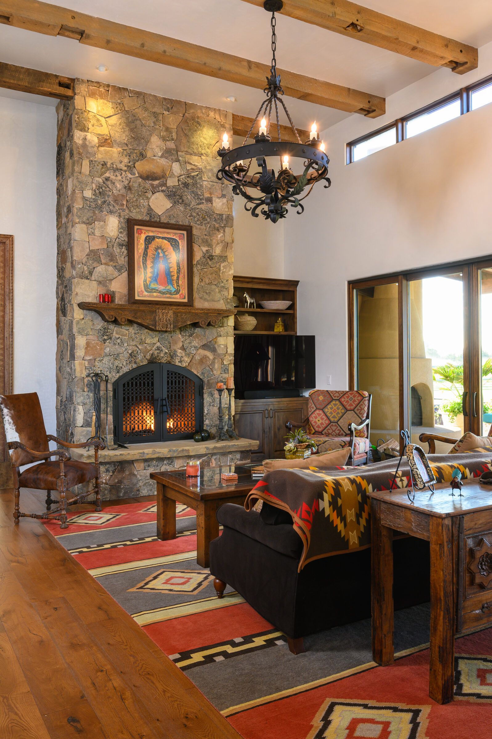 Great room with a floor-to-ceiling stone fireplace, timber beams, and doors opening to the desert, Southwestern Ranch
