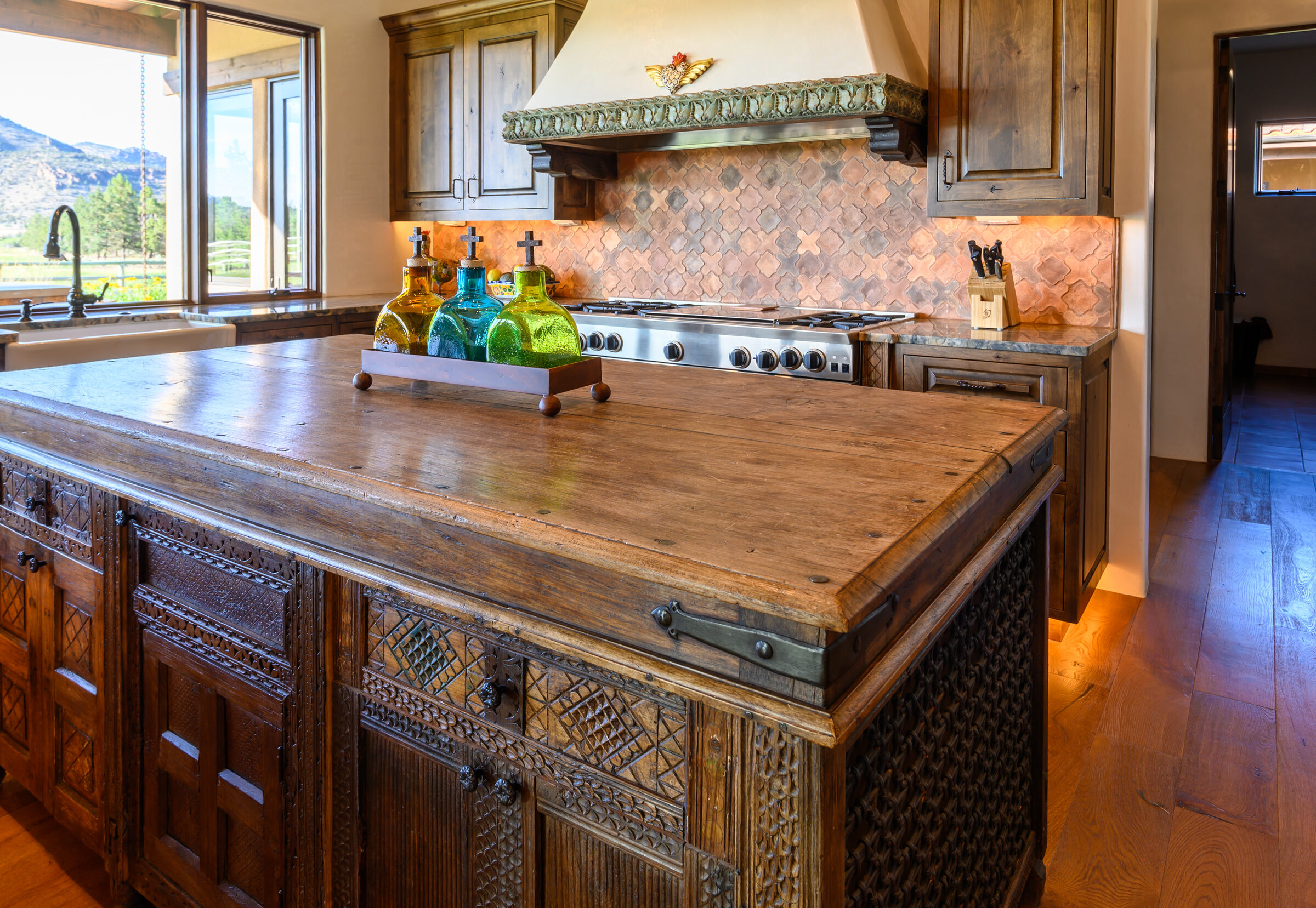 Kitchen with a carved-wood island, hammered-copper backsplash, and stone range hood